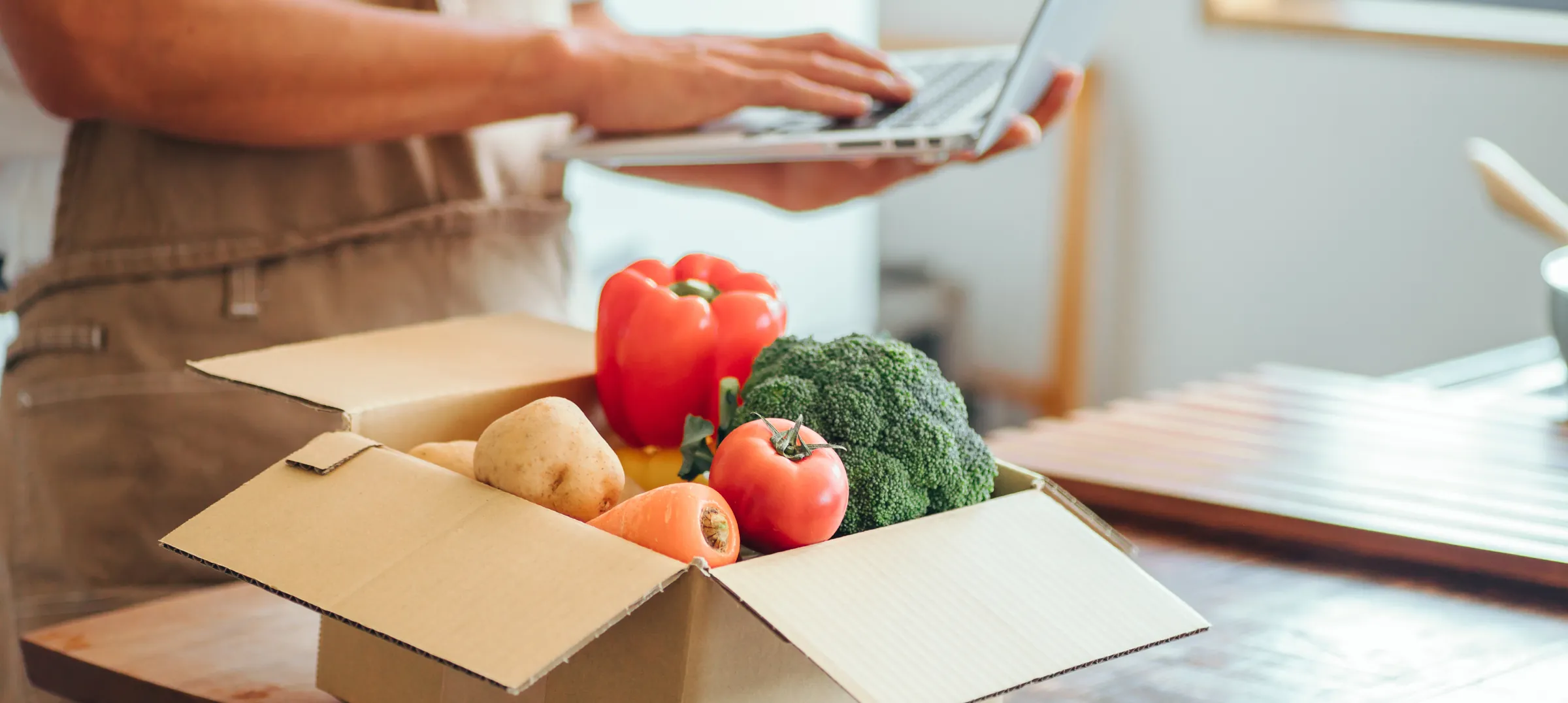 地元の野菜を箱に詰め、パソコンで受注を確認する生産者